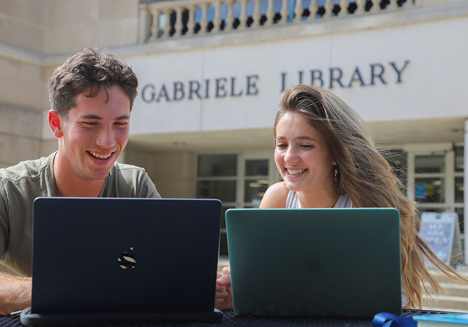 Two students working on a laptop